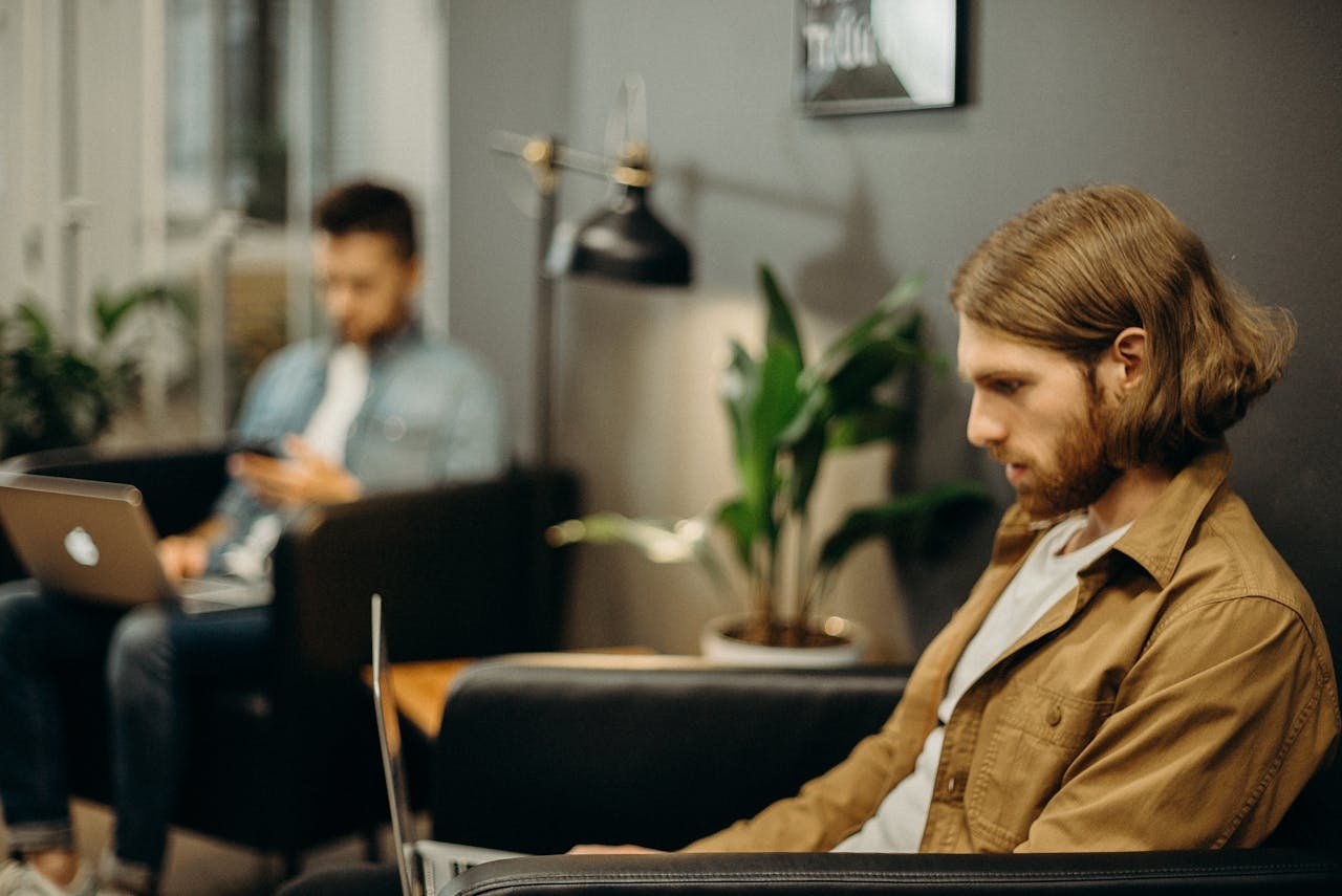 Crafting Captivating Headlines: Your awesome post title goes here Two men using laptops in a modern office, emphasizing remote work trends.
